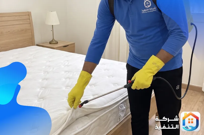 فني من شركة التنفيذ يقوم برش مرتبة سرير لمكافحة الحشرات داخل فندق